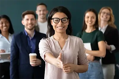 Group of business people with a woman infront with her hand outreached for a handshake