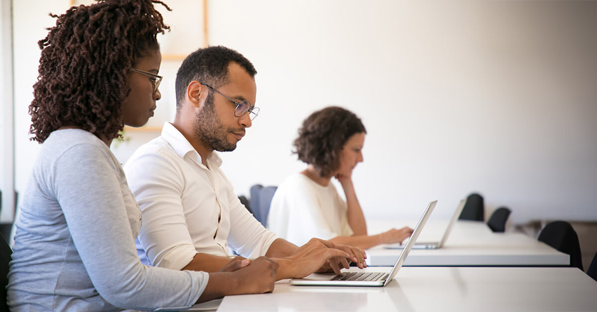 Woman assisting a younger woman completing online forms on a laptop