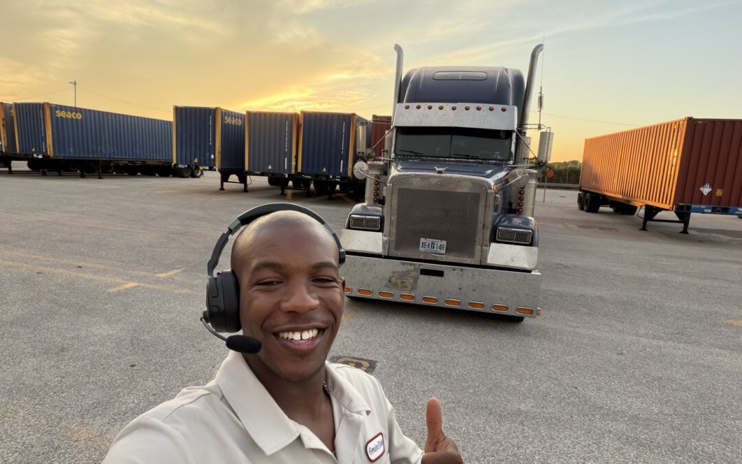 Joshua Theagene smiling in front of a semi truck at a container yard